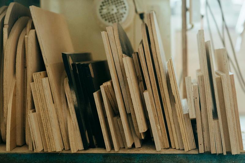 Bilden visar en samling faner- eller plywoodskivor i varierande dimensioner, prydligt uppställda på högkant i en verkstad. Skivorna används ofta inom snickeri och byggprojekt för möbler, inredning eller konstruktion.