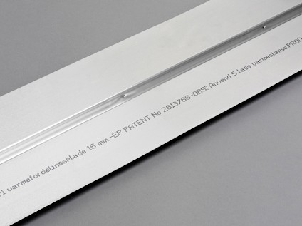 Metallplåt med präglad text som inkluderar "värmefordelingsplade" och patentnummer mot grå bakgrund.