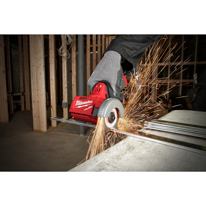 Person i skyddshandskar använder en röd Milwaukee kapmaskin för att skära metall, gnistor flyger.