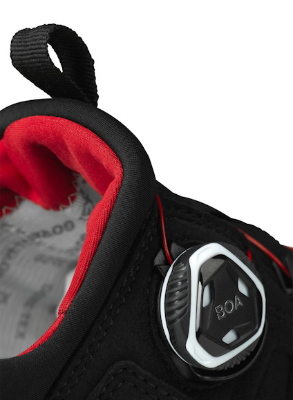 Svart sko med BOA-snörningssystem och röd stoppning runt öppningen.
