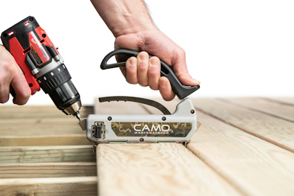 Person använder borrmaskin med CAMO verktyg på trädäck.