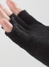 En hand iklädd en stickad, svart halvvante med avklippta fingertoppar.