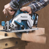Person som sågar trä med en Makita cirkelsåg, damm sprider sig.