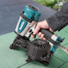 Hand använder en tryckluftdriven spikpistol på grön yta med Makita-logotyp.