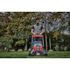 Man mowing lawn with a red and blue lawnmower in a garden setting with trees in the background.