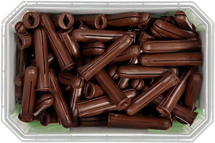 Brun skruvplugg i plast, staplade i en genomskinlig behållare.