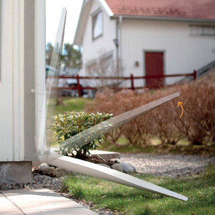 Vit garageport med lyftarm i öppet läge framför ett hus och en trädgård.