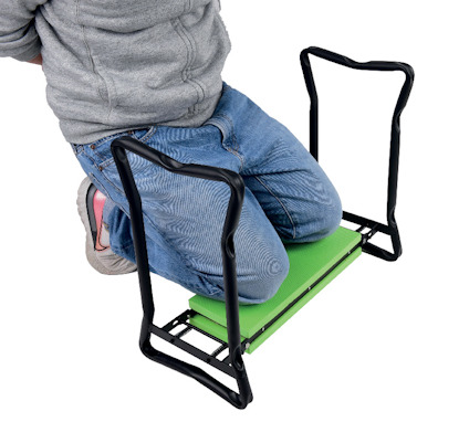 Person sitter på ett hopfällbart knäskydd med grönt säte och svarta handtag.